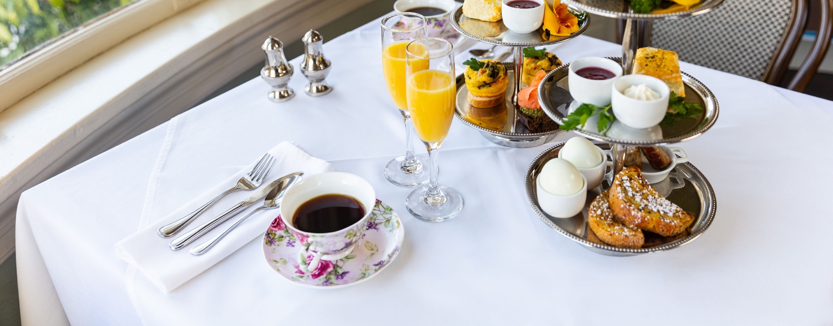 Delicious breakfast, eggs, pastries, tea and drinks on white tablecloth